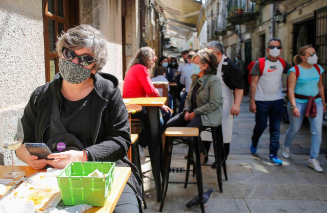 Varias personas en una calle de terrazas de Baiona, en Vigo, Pontevedra, Galicia (España), a 28 de marzo de 2021. El subcomité clínico mantiene el nivel alto de restricciones en el concello de Baiona, lo que conlleva que la hostelería solo puede servir en