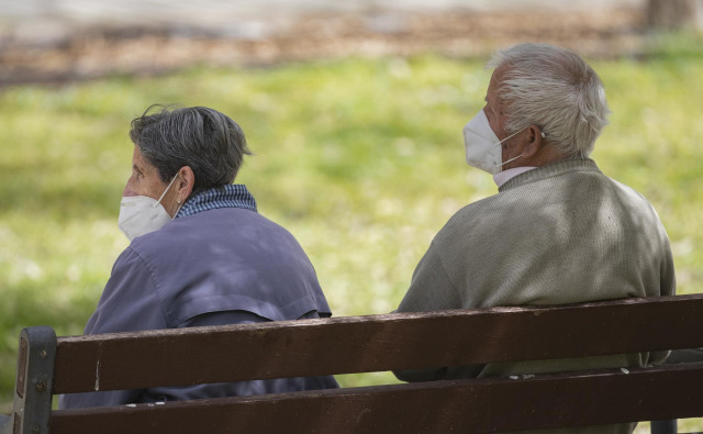 Un hombre y una mujer mayores, sentados en un banco y con mascarilla, en el Parque del Manzanares, el día en que entra en vigor el uso obligatorio de mascarilla incluso con distancia de seguridad, en Madrid (España), a 31 de marzo de 2021.