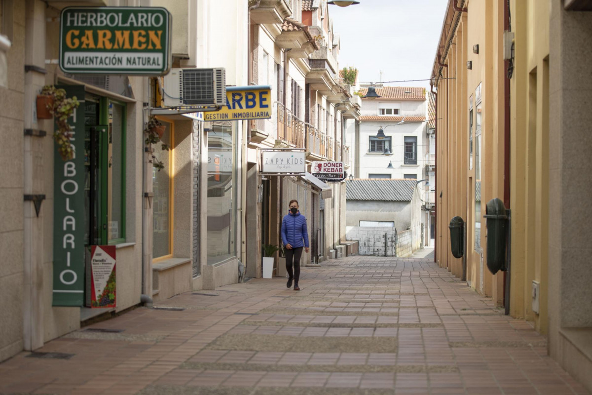 Una mujer camina por una calle de O Grove, el día en que entra en vigor el cierre perimetral del municipio, a 8 de abril de 2021