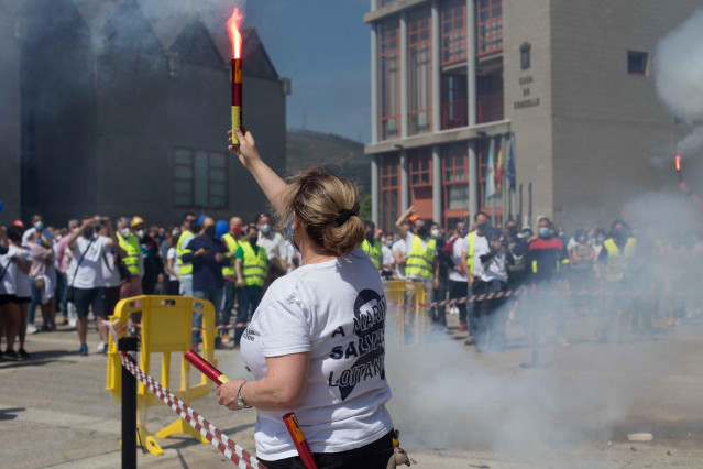 Una mujer sostiene una bengala durante una concentración en conmemoración del año de “lucha” por la planta de aluminio y los puestos de trabajo de Alcoa San Cervo, en la Praza do Concello de Xove, a 30 de mayo de 2021, en Xove, Lugo.