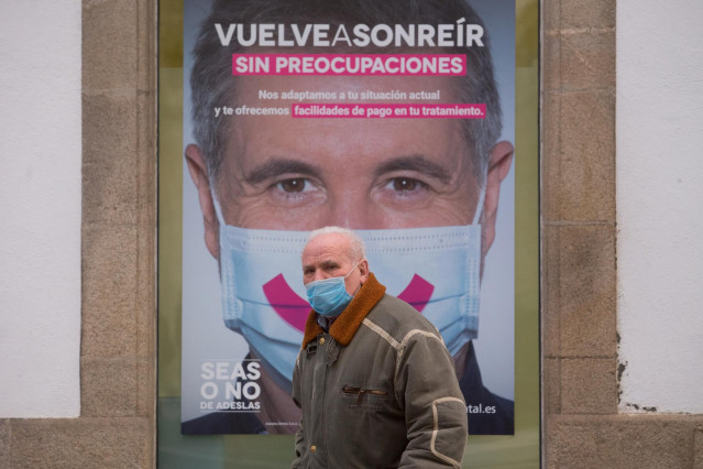 Archivo - Un hombre con mascarilla pasa frente a un cartel publicitario en Lugo, tras el levantamiento del cierre perimetral de la ciudad, en Lugo, Galicia (España), a 30 de diciembre de 2020.  Lugo y Ourense serán las dos únicas urbes gallegas sin cierre