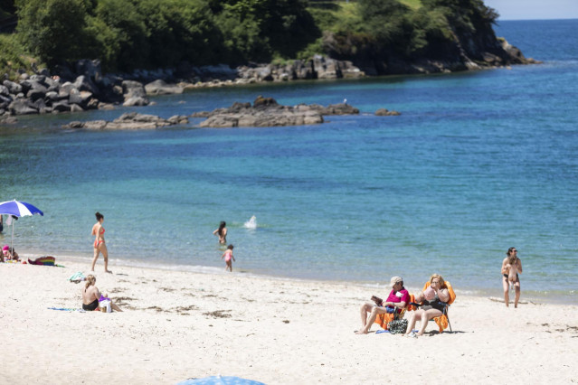 Varias personas se bañan y toman el sol en una playa del municipio de Marín (Pontevedra)