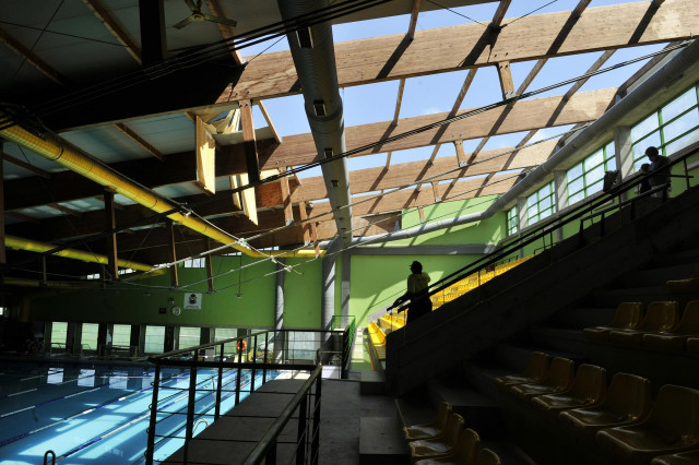 Un operario trabaja en la reconstrucción de un techo levantado por el viento en la piscina olímpica del pabellón municipal de deportes de Ourense tras la tormenta