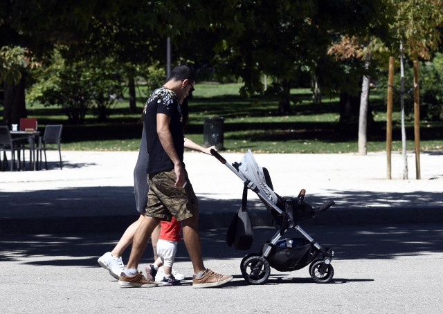 Archivo - Una pareja y su bebé empujan el carrito del mismo en un parque de Madrid.