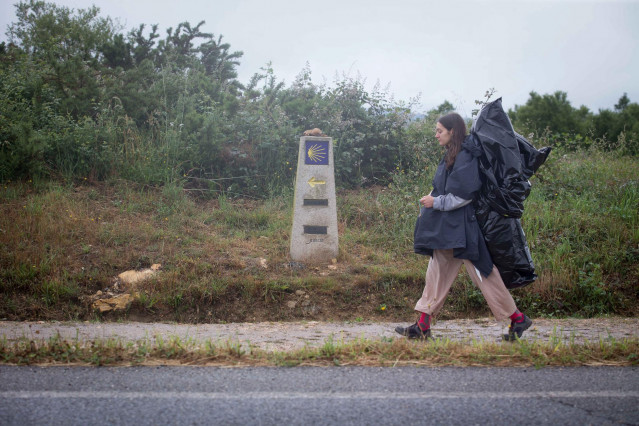 Una peregrina camina hacia Santiago de Compostela por donde transcurre el Camino de Santiago francés