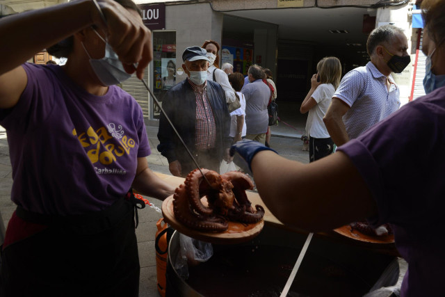 Dos mujeres y una niña comen una ración de pulpo en un restaurante durante la celebración de la Festa do Polbo, a 8 de agosto de 2021, en O Carballiño, Ourense.