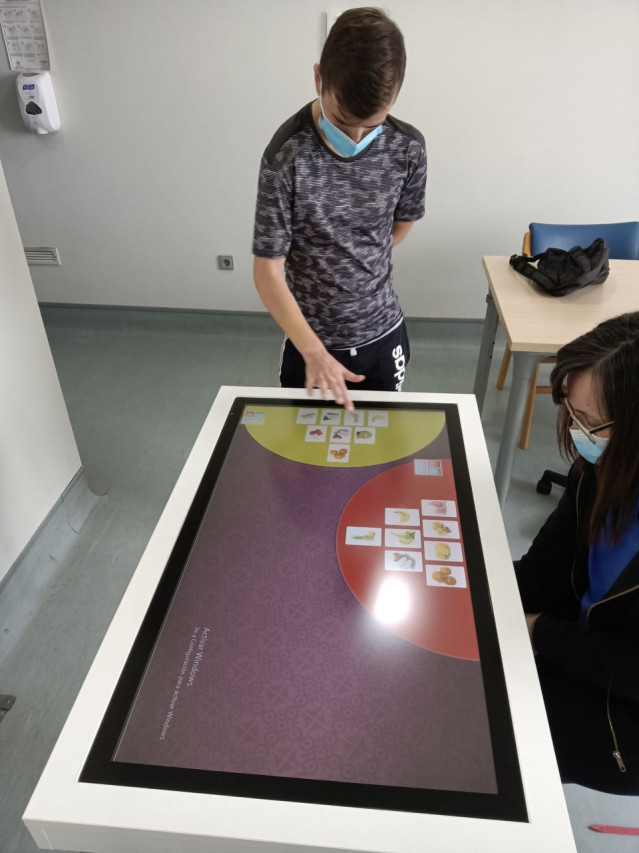 Dos pacientes usando una mesa táctil en la unidad de neurorrehabilitación del hospital Vithas Vigo.