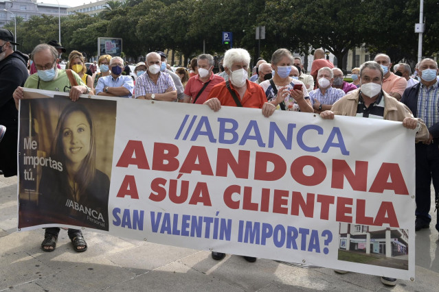 Un grupo de personas sostienen una pancarta durante la manifestación contra el cierre de oficinas de la entidad Abanca ante la sede de Abanca en A Coruña, a 2 de septiembre de 2021, en A Coruña, Galicia, (España).