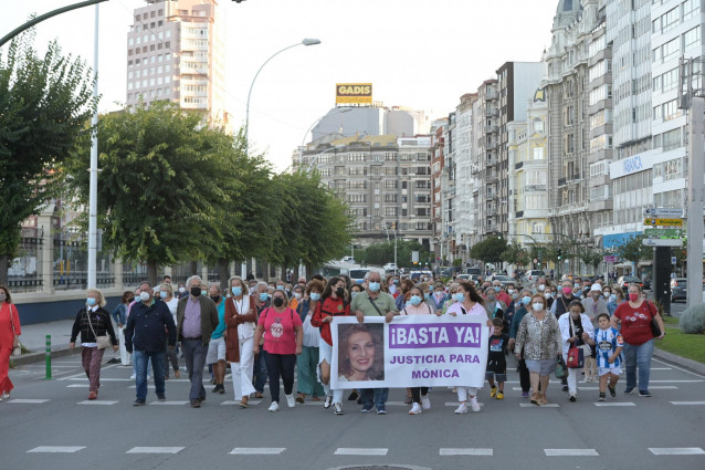Un grupo de personas con una pancarta en la que se lee: ''¡Basta ya!', participa en una manifestación contra el crimen machista de una mujer en O Birloque