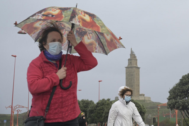 Varias personas pasean en el Paseo Marítimo de A Coruña bajo la lluvia