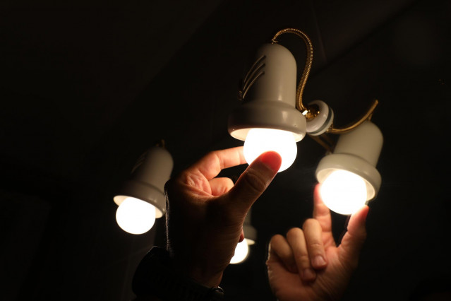 Una persona cambia la bombilla de una lámpara, el día en que el precio de la luz bate un récord histórico alcanzando los 124,45 euros por megavatio hora, a 30 de agosto de 2021, en Madrid, (España). Supone una subida de dos euros respecto al máximo anteri