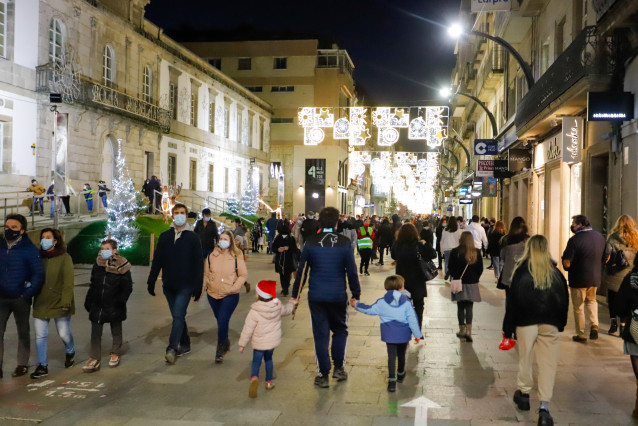 Archivo - Transeúntes pasean bajo las luces navideñas, llevando mascarilla, alguno con gorro navideño, en Vigo, Galicia (España), a 25 de diciembre de 2020.