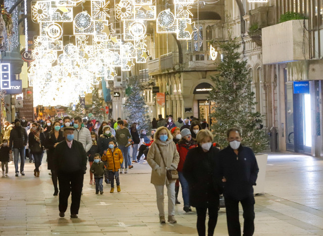Archivo - Transeúntes pasean bajo las luces navideñas, llevando mascarilla, en Vigo, Galicia (España), a 25 de diciembre de 2020. Vigo está cerrada perimetralmente, pero abierta entre el 23 y 25 de diciembre para permitir encuentros familiares.