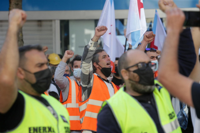 Varios hombres lanzan consignas y alzan el puño durante una concentración conjunta de trabajadores de las fábricas de Alcoa y de Vestas situadas en A Mariña (Lugo), frente a la Subdelegación del Gobierno, a 10 de octubre de 2021