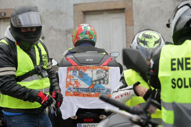 Un hombre lleva enganchada a su moto una pancarta donde se lee 