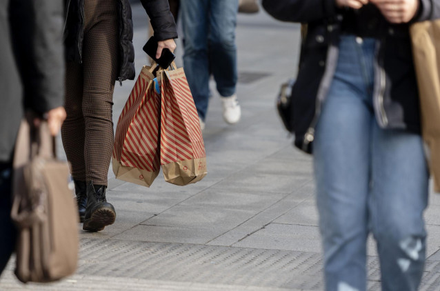 Una mujer camina con bolsas con compras, a 25 de noviembre de 2021, en Madrid (España). El Black Friday se celebra después del día de Acción de Gracias y se caracteriza por que en él se lanzan ofertas en los comercios de cara a las compras navideñas.