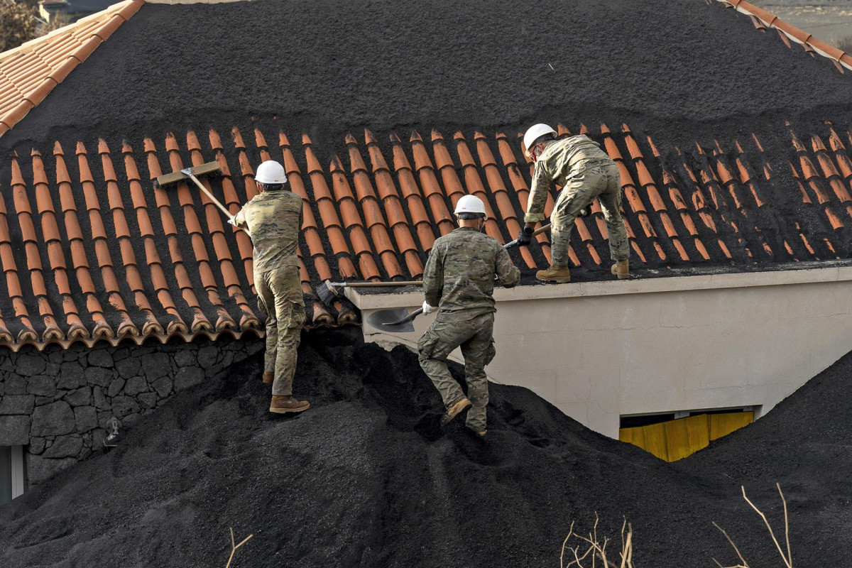 Militares retiran ceniza del tejado de una casa, en la zona de exclusión próxima al volcán de Cumbre Vieja