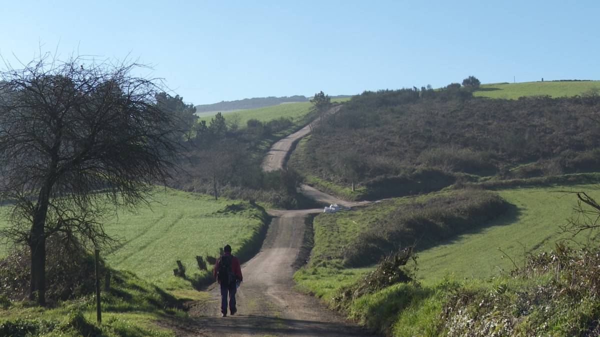 Un peregrino que realiza el Camino de Santiago en el mes de enero de 2022 avanza por un camino entre Negreira y Fisterra, última parada para muchos caminantes