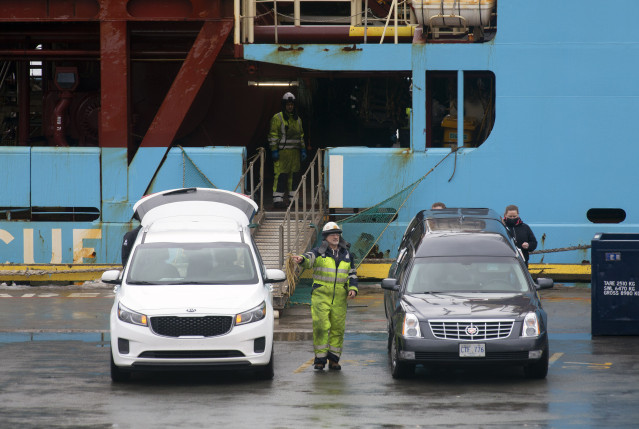 Personal portuario supervisa los coches fúnebres donde serán trasladados los cuerpos de los dos pescadores naufragados en Terranova que hoy han sido transportados en el buque ‘Nexus’ que ha llegado al Puerto de San Juan de Terranova