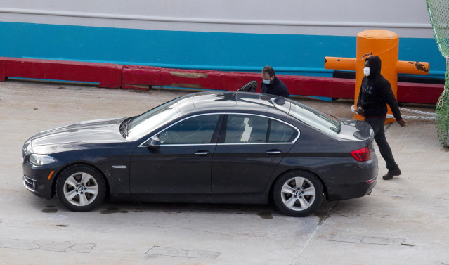 Eduardo Rial Padín (i), y Samuel Kwesi, tripulantes del pesquero gallego que naufragó en aguas canadienses, se introducen en un vehículo tras bajar del pesquero español 'Playa Menduiña Dos' a su llegada al Puerto de San Juan de Terranova, a 19 de febrero