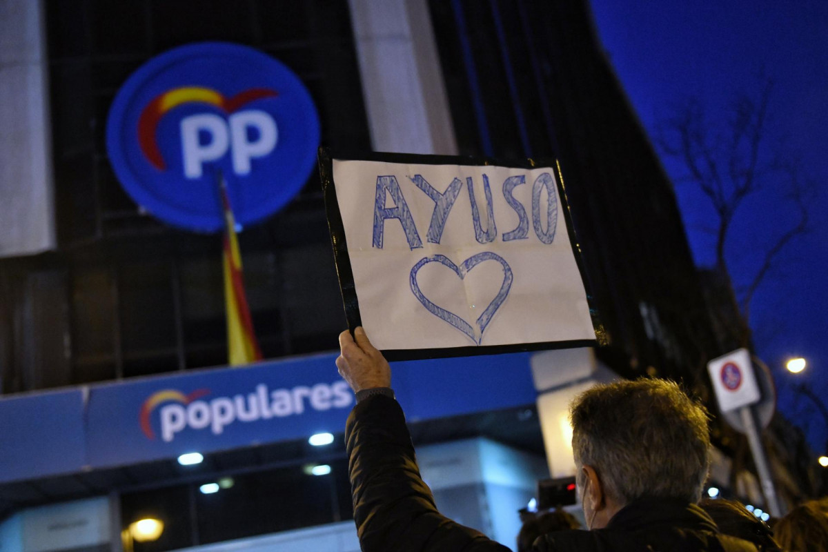 Un hombre sostiene un cartel en el que se lee Ayuso con un corazón