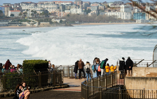 Un grupo de personas observa el fuerte oleaje que se aproxima al paseo marítimo, a 25 de febrero de 2022, en Santander, Cantabria (España).