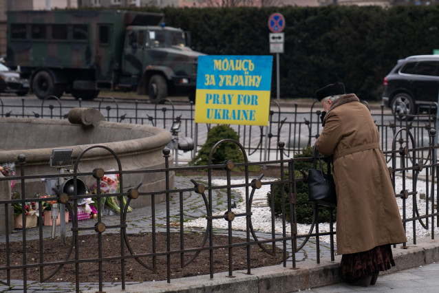 Una mujer mayor observa las flores, que homenajean a los fallecidos por la guerra, junto a un cartel que dice 'Reza por Ucrania''. Ucrania cumple nueve días sumida en un conflicto bélico tras el inicio de los ataques por parte de Rusia. Según las últimas