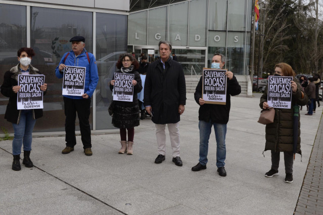 Un grupo de personas participa en una concentración contra las obras en San Pedro de Rocas al considerar que “causarán graves daños en un entorno protegido”, a las puertas de los Juzgados de Ourense donde se iba a celebrar un juicio que finalmente ha sido