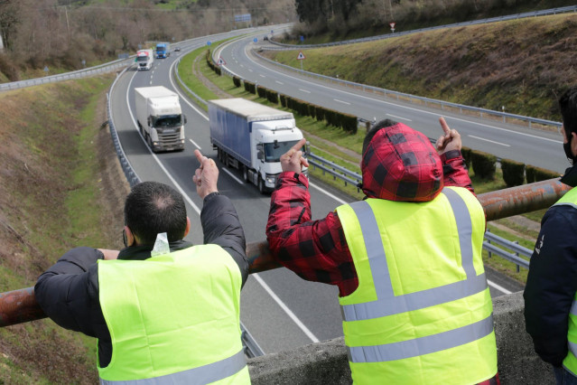 Dos miembros de un piquete insultan y hacen gestos a los camiones que pasan en dirección A Coruña escoltados por la Guardia Civil, durante el cuarto día de paros en el sector de los transportes, a 17 de marzo de 2022, en Baralla, Lugo, Galicia (España). L