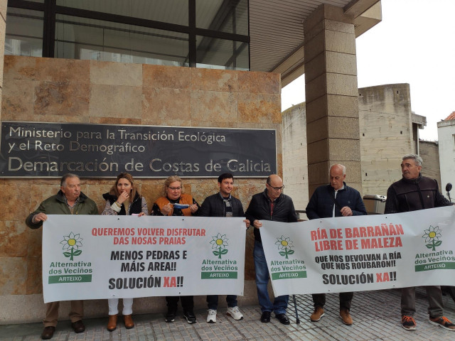 Representantes de Alternativa dos Veciños de Arteixo se han concentrado este miércoles delante de las oficinas de la Demarcación de Costas de A Coruña para exigir la limpieza del cauce de la Ría de Barrañán y la retirada de las piedras de los arenales