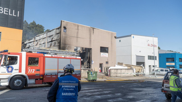 Un bombero observa las instalaciones de la nave industrial de poliéster donde se ha producido un incendio que la ha dejado calcinada, a 10 de mayo de 2022, en Bueu (Pontevedra).