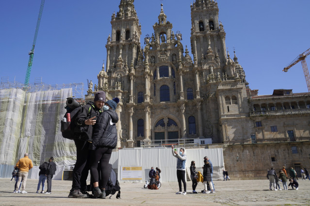 Archivo - Una pareja de peregrinos se echan una foto en la Catedral de Santiago durante el puente de San José, en Santiago de Compostela, en A Coruña, Galicia (España), a 20 de marzo de 2021. Paradores ha lanzado una tarifa especial para que los peregrino