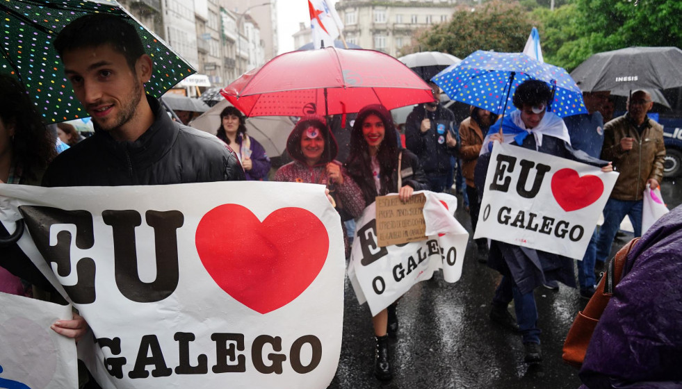 Varias personas con paraguas y carteles en los que se lee: 'Eu O Galego (hablo gallego)', participan en una manifestación, bajo el lema: ‘Queremos Galego’, a 17 de mayo de 2022, en Santiago de Co
