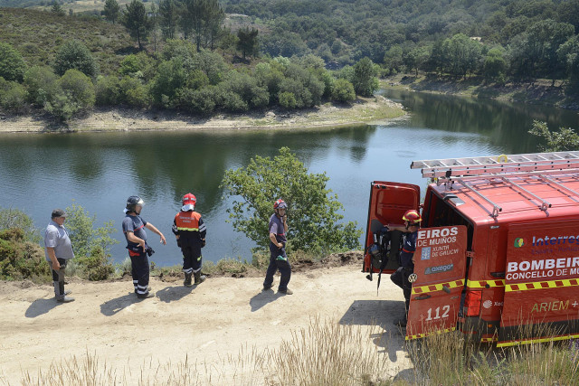 Efectivos de bomberos en el lugar donde ha caído un camión al agua tras realizar tareas de desbroce, en el embalse de As Conchas, en Muíños, Ourense, Galicia (España). El hecho se produjo cuando el camión cayó al río Limia cuando circulaba por una pista f