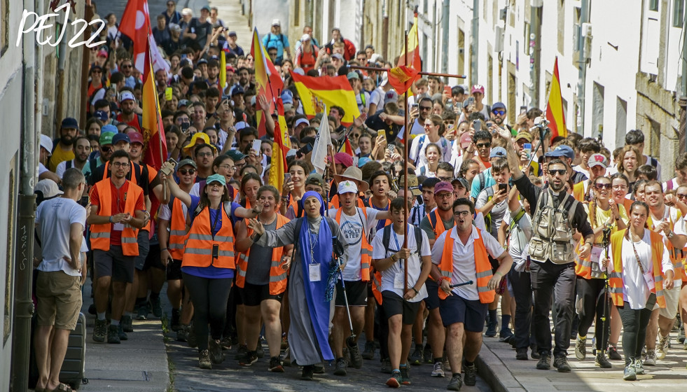 Llegada de jóvenes peregrinos ocupando todo el ancho de la calzada en el Barrio de San Pedro y enarbolando banderas españolas
