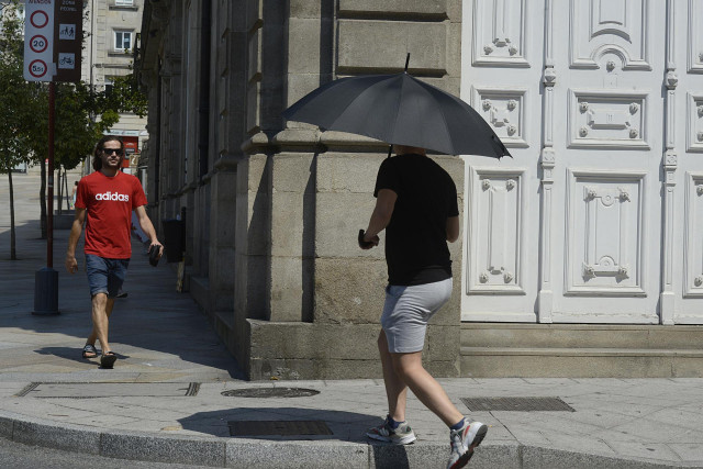 Dos personas caminan por una vía en plena ola de calor, a 12 de julio de 2022, en Orense, Galicia (España). Los termómetros de la práctica totalidad del territorio gallego alcanzarán valores “extremos” debido a la ola de calor que comenzó la semana pasada