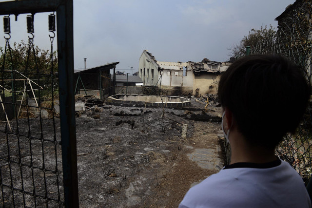 Un vecino observa una zona de viviendas afectadas por el fuego, a 18 de julio de 2022, en O Barco de Valdeorras, Ourense, Galicia (España). La superficie arrasada por los principales incendios registrados en Galicia ya supera las 9.000 hectáreas, según la