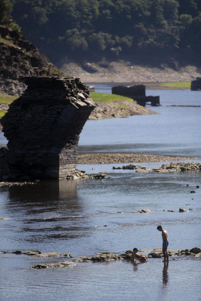 Varios jóvenes caminan por las aguas muy poco profundas del Rio Miño a su paso por Portomarín.