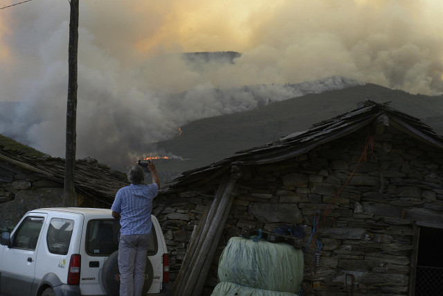 Un hombre fotografía las llamas del incendio, a 10 de agosto de 2022, en Laza, Ourense, Galicia (España).