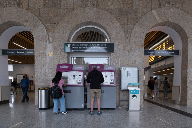 Dos personas compran billetes en los cajeros de venta automática en la estación de trenes, a 24  de agosto de 2022, en Santiago de Compostela, A Coruña, Galicia, (España). Los usuarios de Renfe en Galicia pueden adquirir desde hoy los abonos gratuitos.
