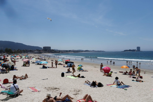 Archivo - Varias personas se bañan y toman el sol en la playa de Samil
