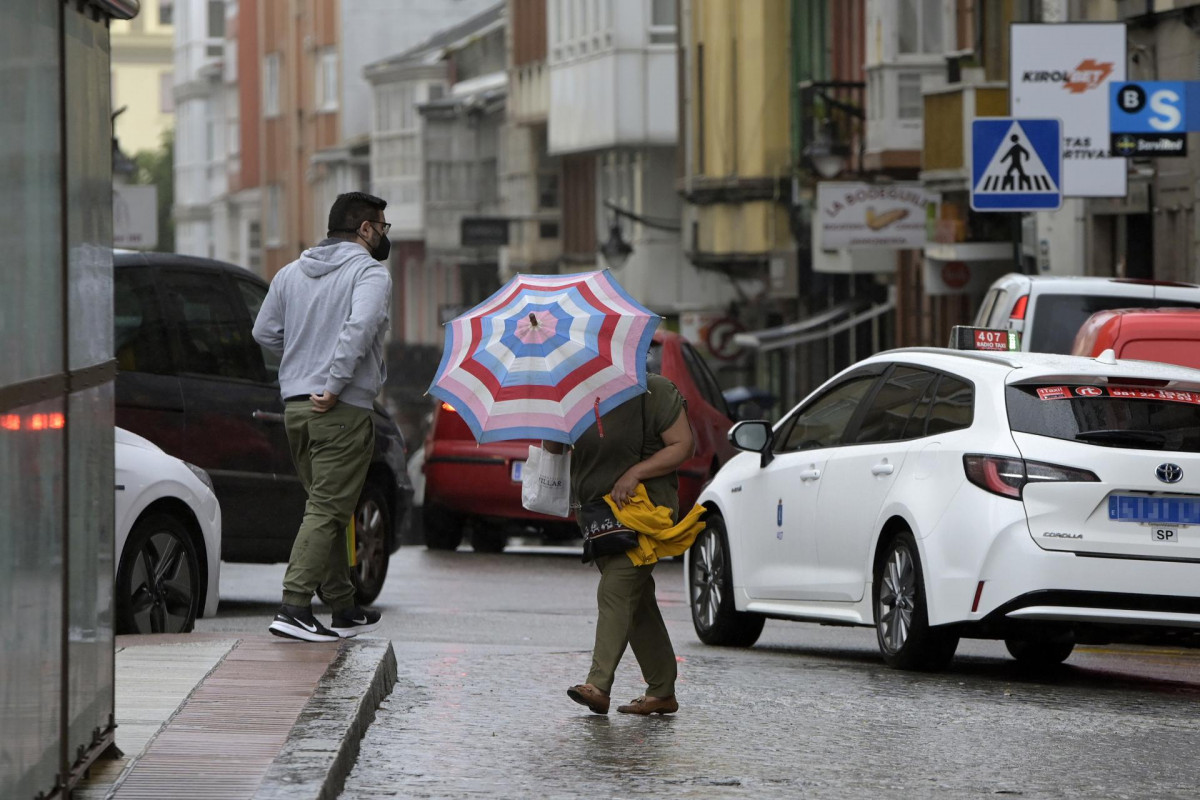 Archivo - Una mujer se resguarda del viento y la lluvia con un paraguas en el centro de la ciudad, a 19 de junio de 2022, en A Coruña, Galicia, (España). La inestabilidad se mantendrá en Galicia al