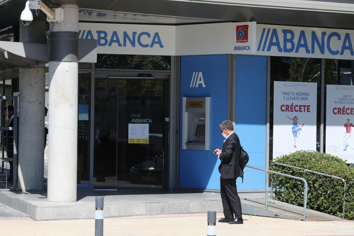 Archivo - Un hombre pasa al lado de una sucursal de Abanca, en Madrid, (España).