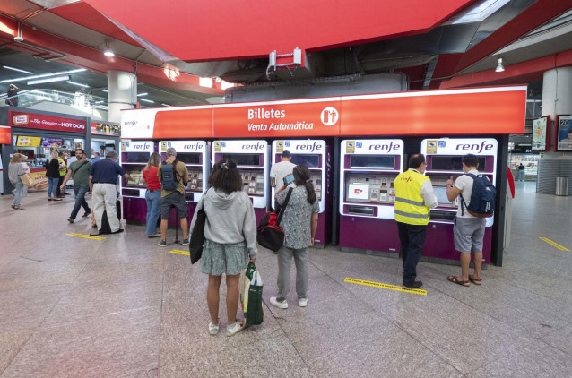 Archivo - Varias personas adquieren sus billetes en las taquillas de venta automática de la estación de tren de Atocha