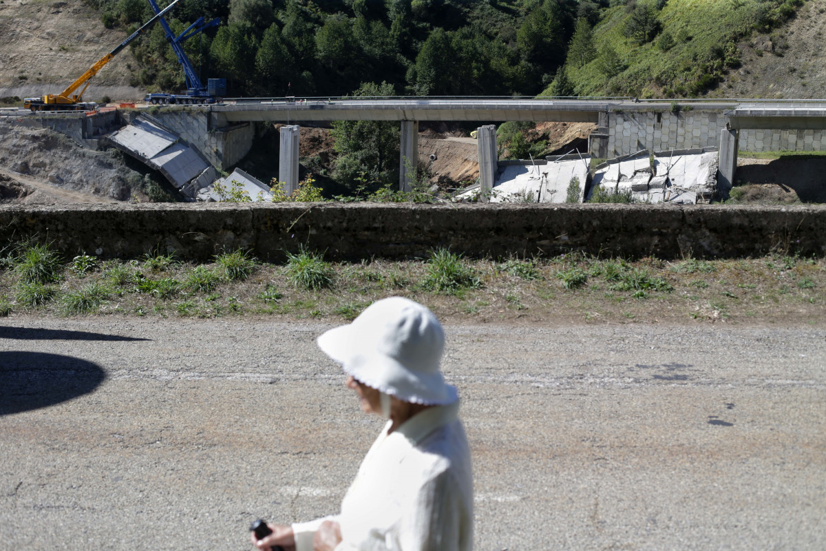 Una mujer camina por la carretera mientras se realiza el desmontaje de las pilas 1 y 2 del viaducto de O Castro, en el kilómetro 430 sentido A Coruña de la autovía A-6.