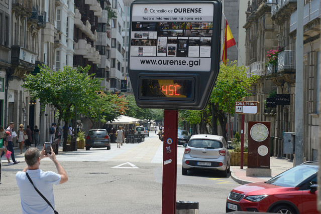 Archivo - Un hombre hace una fotografía a un termómetro en la calle que marca 45 grados, a 12 de julio de 2022, en Ourense, Galicia