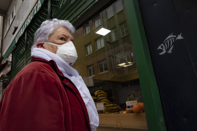 Archivo - Una mujer protegida con mascarilla se dirige a la entrada de un establecimiento alimenticio en A Coruña