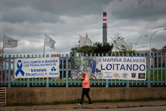 Archivo - Una persona pasa delante de una pancarta, colocada por los trabajadores en la valla de la fábrica de Alcoa en San Cibrao, un día después de que los trabajadores alcanzaran un acuerdo con la empresa, a 29 de diciembre de 2021, en San Cibrao, Cerv