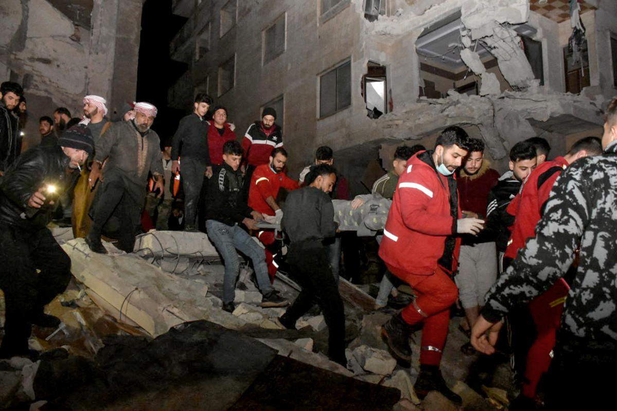 Foto publicada por la agencia oficial de noticias siria SANA muestra a los rescatistas y personas que transportan a una persona herida de los escombros de un edificio destruido de 8 pisos en el terremoto