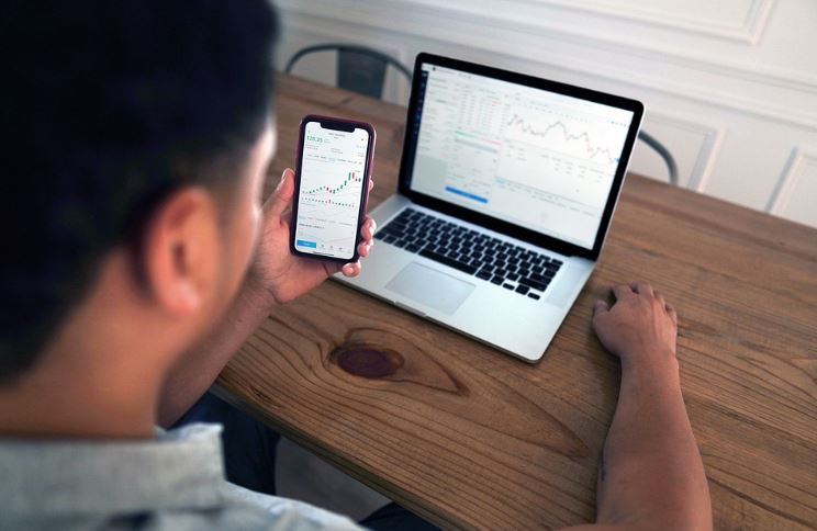 Trabajando con el móvil y el ordenador en una foto de The Investor Post publicada bajo licencia por Pixabay